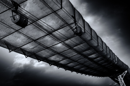 Aging industrial conveyor belt carries cement materials over metal safety netting. This abstract industry based wall art relies on heavy post-processing to create a sense of surreal attention.  The fantastic blue skies made the background for this piece rの写真素材
