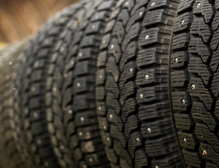Single row of popular car winter snow tyres with metal spikes for better grip and safety in snow conditions. Essential transport item for wintery conditions.の写真素材