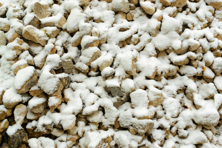 Fresh light snow falls onto many stones, suggesting a travel on construction hazard.の写真素材