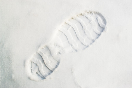 Single human bootprint in a diagonal composition in fresh crisp white snow