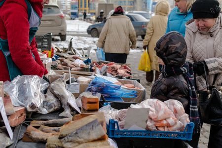 UFA, RUSSIA - NOVEMBER 12, 2015: Young Russian by looks at fresh fish on display at a local fishmonger stall in Ufa, Russia during November of 2015. The fish are a valuable food resource for the winter months ahead.のeditorial素材