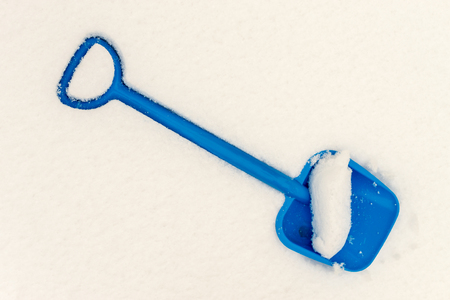 Childs blue plastic spade or shovel rests in fresh snow during winterの写真素材