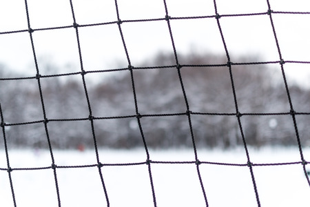 Frayed sports netting at a local public park with a white snow backgroundの写真素材