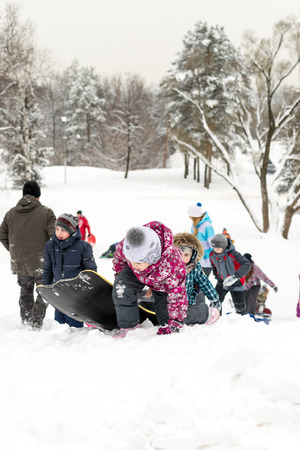 UFA - RUSSIA 16TH JANUARY 2016 - Children enjoy the fresh snow by using improvised slides and sleds to slide down snow banks in "Victory Park" in Ufa, Russia in January 2016.のeditorial素材