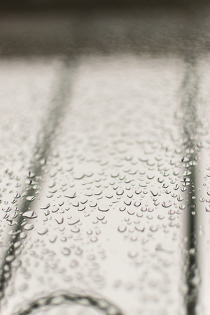Condensation forms water drops on a home glass window. A grey sky in the background with railings allows ample copy space for domestic or engineering designs.の写真素材