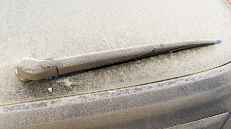 Rear windscreen car window wiper frozen with frost in a cold weather environment.
