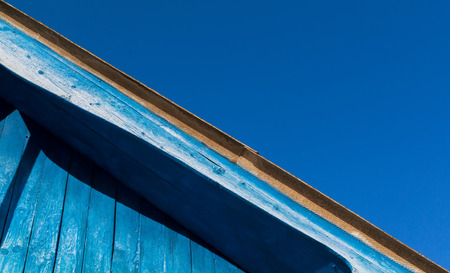 Old faded blue wooden roof abstract set against a blue sky background. Copy space area for designs and architecture themed ideas and text. Natural sunlight and worn wood pattern.の写真素材