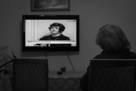 UFA - RUSSIA 3RD MARCH 2016 - An elderly woman sits and watches a news channel on television in a...