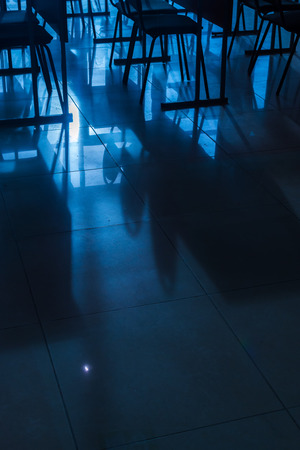 Rows and lines of empty conference chairs caught in natural sunlight in a classroom school environment. Blue toned image with copy space area for meetings or business designs. Vertical composition with nobody present.の写真素材