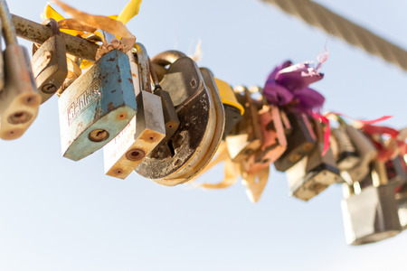 Line of various old rusting metal padlocks in different shapes locked and secured. Blue clear background sky area with copy space for eternal love and symbolic concepts or ideas of romance. Colour image.の写真素材