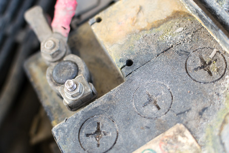 Closeup image of a corroded and defective car battery showing erosion of the terminals and residue...