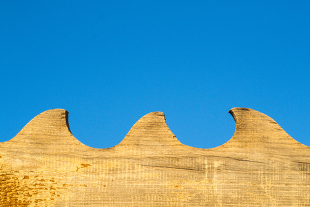 Aged yellow wood in a wave pattern with a blue summer sky background