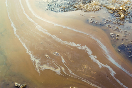 Vibrant colours of a mechanical oil spill on water creating a polluted water source