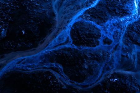 Blue toned oil spill on water creating environmental contamination of nearby water sources