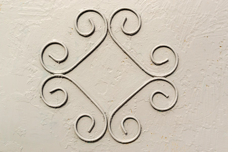 Single pattern of wrought iron forming a symmetrical pattern on a industrially grey paint background