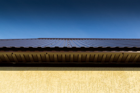 Domestic house photograph of a building roof with vibrant colours and a clear blue sky. Copy space...