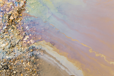 Abstract of bright vibrant oil spill shapes of pollution on the surface of water. Patterns of multi-coloured pollutants releasing hazardous chemicals into the environment.の写真素材