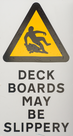 Health and safety hazard warning sign stating Deck Boards May Be Slippery When Wet for shipping or boat designs.の写真素材