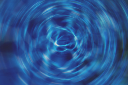 Spinning water whirlpool effect on the surface of cool blue water in natural sunlightの写真素材