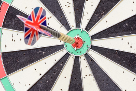 English Union Jack flag metal dart that has hit the red bullseye of a dartboard.