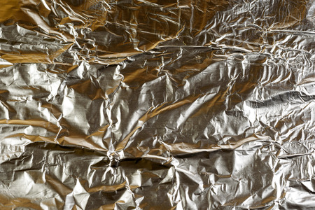 Crumpled Aluminum tin foil texture with light reflections on the shiny metallic silver wrapping