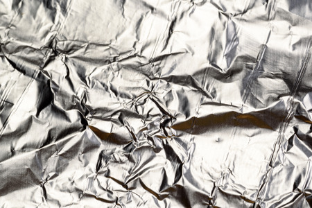 Crumpled Aluminum tin foil texture with light reflections on the shiny metallic silver wrapping