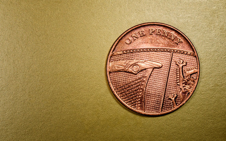 One penny English currency coin in a macro close-up on a rich luxurious golden background. Copyspace area for finance, banking, and economics designs and concepts.の写真素材