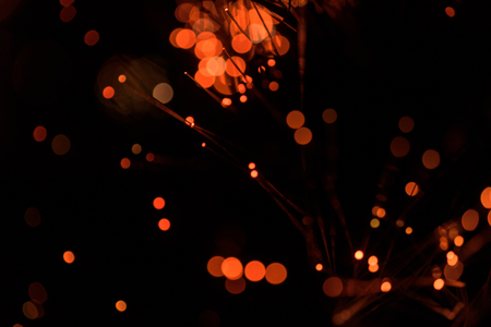 Abstract celebration festive lights using a defocused bokeh effect with a black background. The sparkling orange colored lighting is created from the blur of intense Christmas decorations.の写真素材