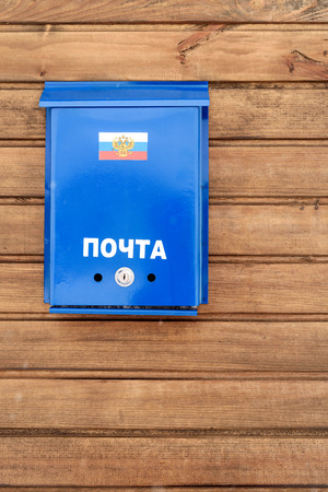 Russian post box with flag of Russia and in blue painted metal, set on a wooden exterior fence.の写真素材