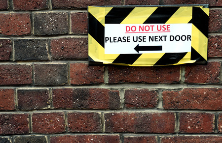 Do Not Use Please use next door sign on old brick wallの写真素材