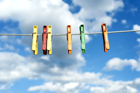 An assortment of brightly colored washing pegs and clothespins on a outdoor washing line with bright...