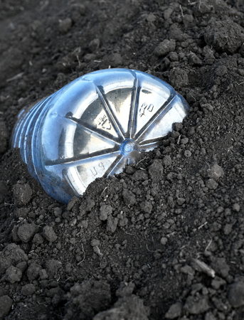 5 litre plastic PET bottle discarded ad left in brown soil with copyspace area for recycling and environmental issue designsの写真素材