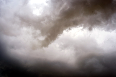 Stormy clouds in the sky with shades of black and grey and fragments and wisps of rainの写真素材