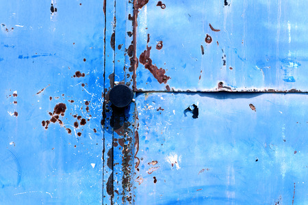 Old retro vintage door handle with a blue flaking paint metal backgroundの写真素材