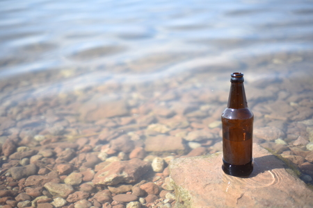 Single brown glass bottle with a rippling water background and natural sunlightの写真素材