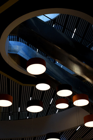 Circular Modern lights hang from the ceiling of a modern building interiorの写真素材