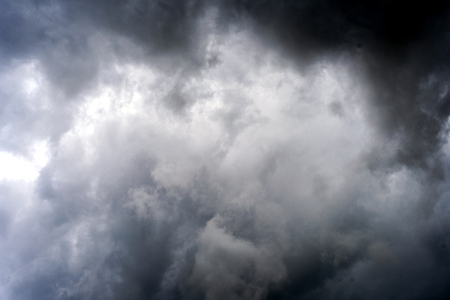 Stormy clouds in the sky with shades of black and grey and fragments and wisps of rainの写真素材