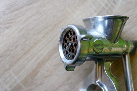 Closeup of a hand operated manual mincemeat making machine showing the cutting wheel and bladesの写真素材