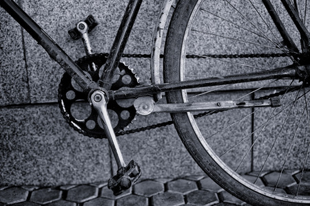 Closeup of an old blue vintage retro bicycle with pedals and chain cog against a concrete background