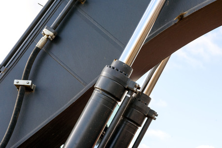 Black hydraulic arm of a digger excavator earthmoving machine with a sky backgroundの写真素材