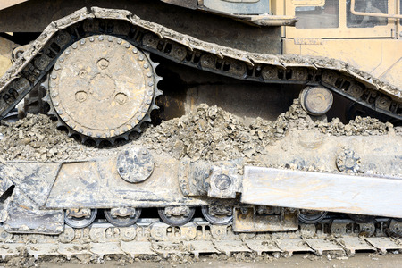 Mud clay encrusted earth moving tracks of a digger excavator machine in color with copy space area for gravel aggregate based ideas and designsの写真素材