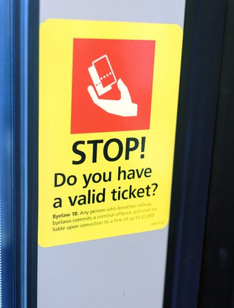 Red and yellow train ticket reminder sign warning about travelling without known as fare evasion