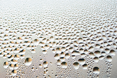 Condensation formed on glass surface of a window with silver water dropsの写真素材