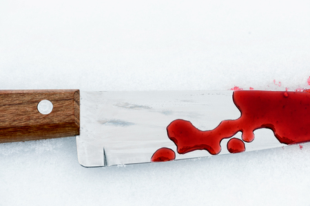 Sharp metal kitchen knife edge used as a violent murder weapon with blood drops on a white snow background. Blade covered in violence with copy space area for domestic crime criminal designsの写真素材