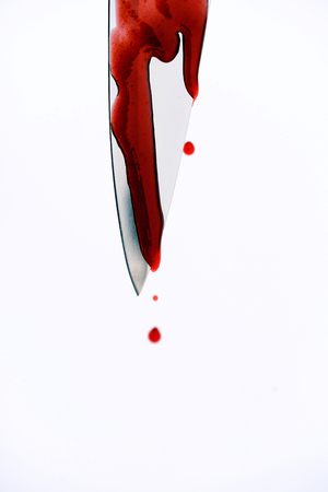 Sharp metal kitchen knife with blood dripping from its edge in a vertical shotの写真素材