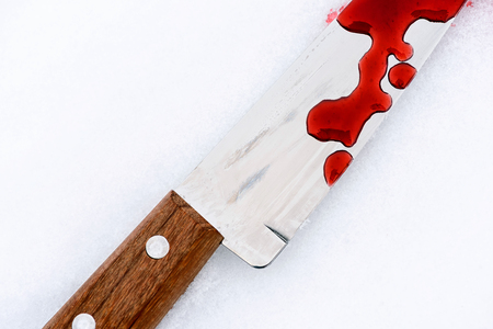 Sharp metal kitchen knife edge used as a violent murder weapon with blood drops on a white snow background. Blade covered in violence with copy space area for domestic crime criminal designsの写真素材