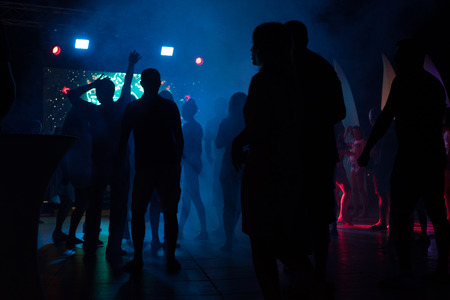 People dance at a nightclub at night in silhouette with different color lights and digital effectsの写真素材