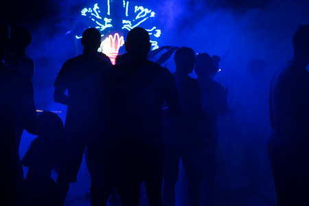 People dance at a nightclub at night in silhouette with different color lights and digital effects