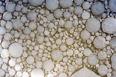 Overhead abstract image of used cooking fat congealed on the surface of water.