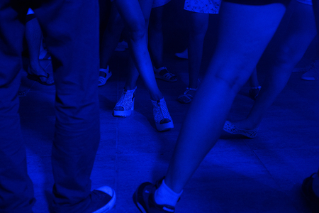 Peoples feet and legs dancing at a nightclub with diffrerebt color lights and smoke effects with no facesの写真素材